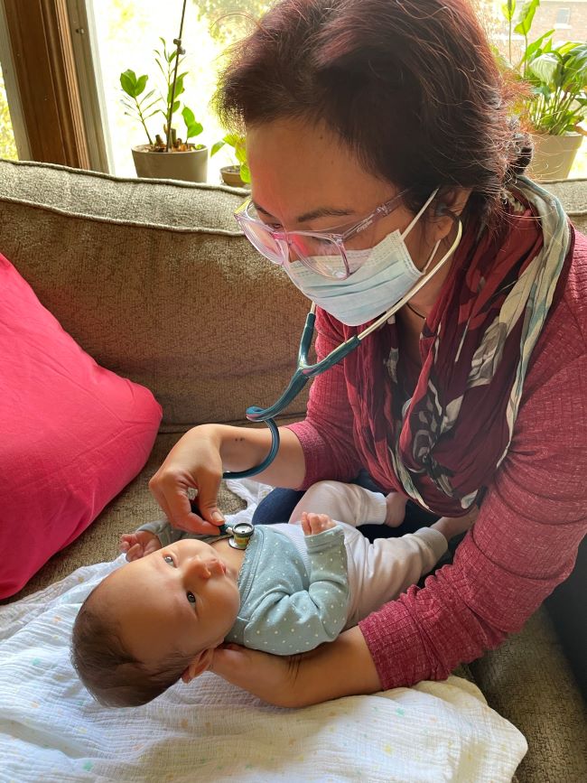Midwife and AOM President Jasmin Tecson performs clinical examination of newborn Rafi Shoshana Adjemian-Nestel with stethoscope at a postpartum home visit.