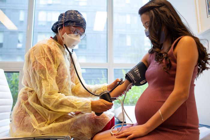 Midwife checks pregnant client's blood pressure at a prenatal appointment