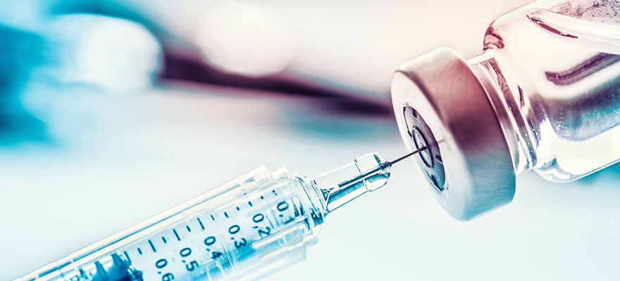 Picture of a syringe drawing up medication from a bottle.