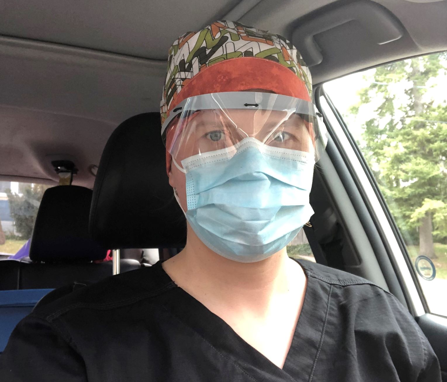 Midwife Ali McCallum wearing personal protective equipment, in her vehicle on route to visit a client at home