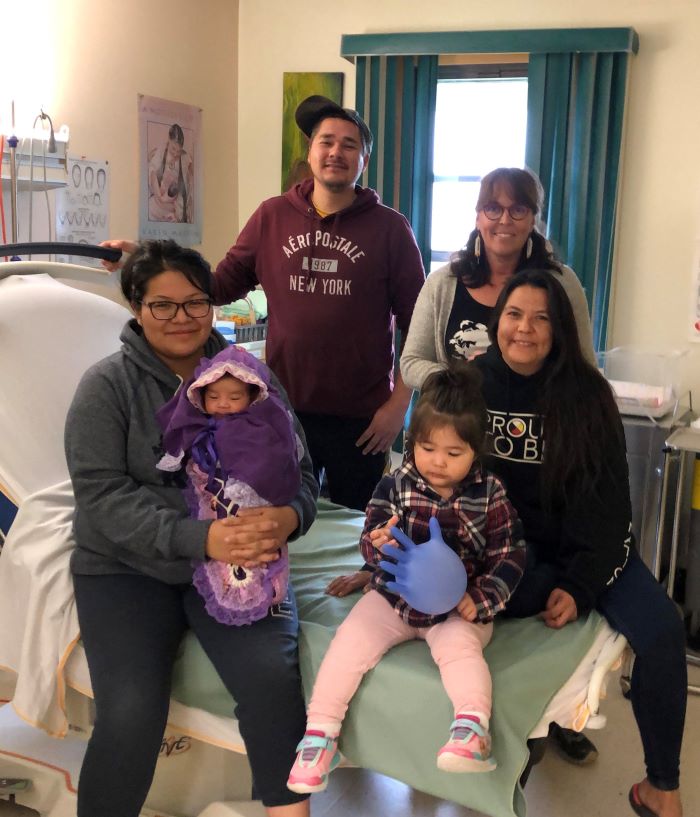 The Sutherland-Kioke family, Robert, Michelle, Raelynn and baby Kiera, pose alongside Neepeeshowan staff Christine Roy, RM, and second attendant Jennifer Tookate with the new birth bed at Weeneebayko Area Health Authority Hospital, Attawapiskat, ON. 