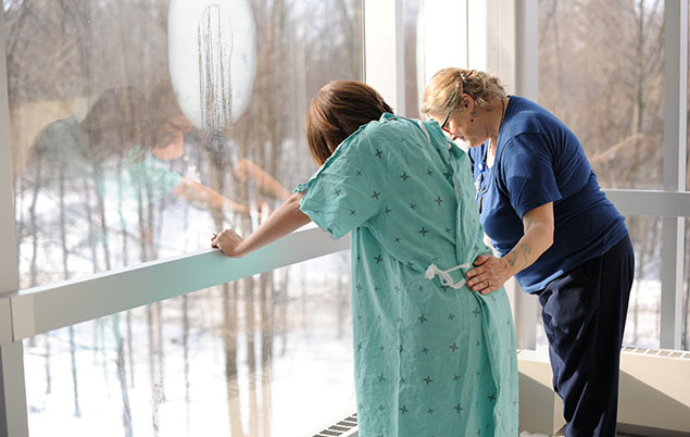 Photo of a labouring person and their midwife standing at a window in a birth centre.