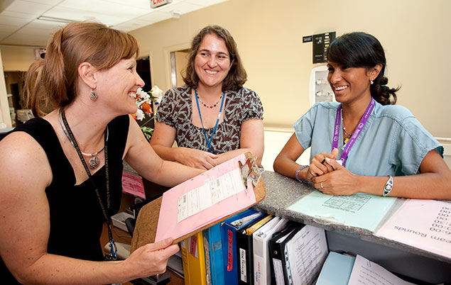 Photo of a midwife talking with other hospital staff.