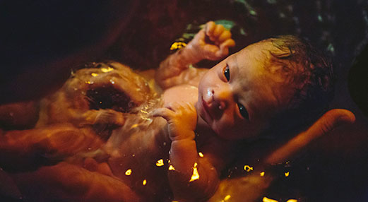 Picture of hands holding a baby in water.