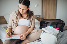 Pregnant person writing in notebook.