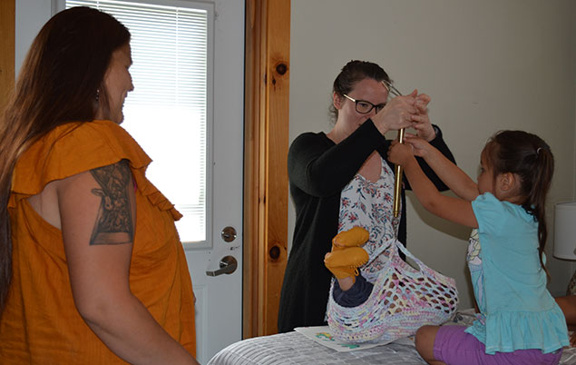 Photo of midwife weighing baby with family at Six Nations birth centre.