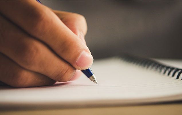 Photo of a hand making notes in a notebook.