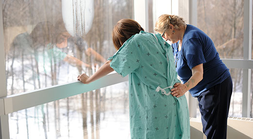 Photo of a labouring person with their midwife standing at a window in a birth centre.