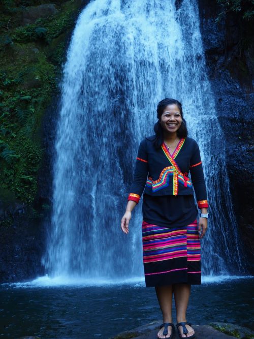 Midwife Bounmy Inthavong standing in front of a waterfall in Lao PDR.