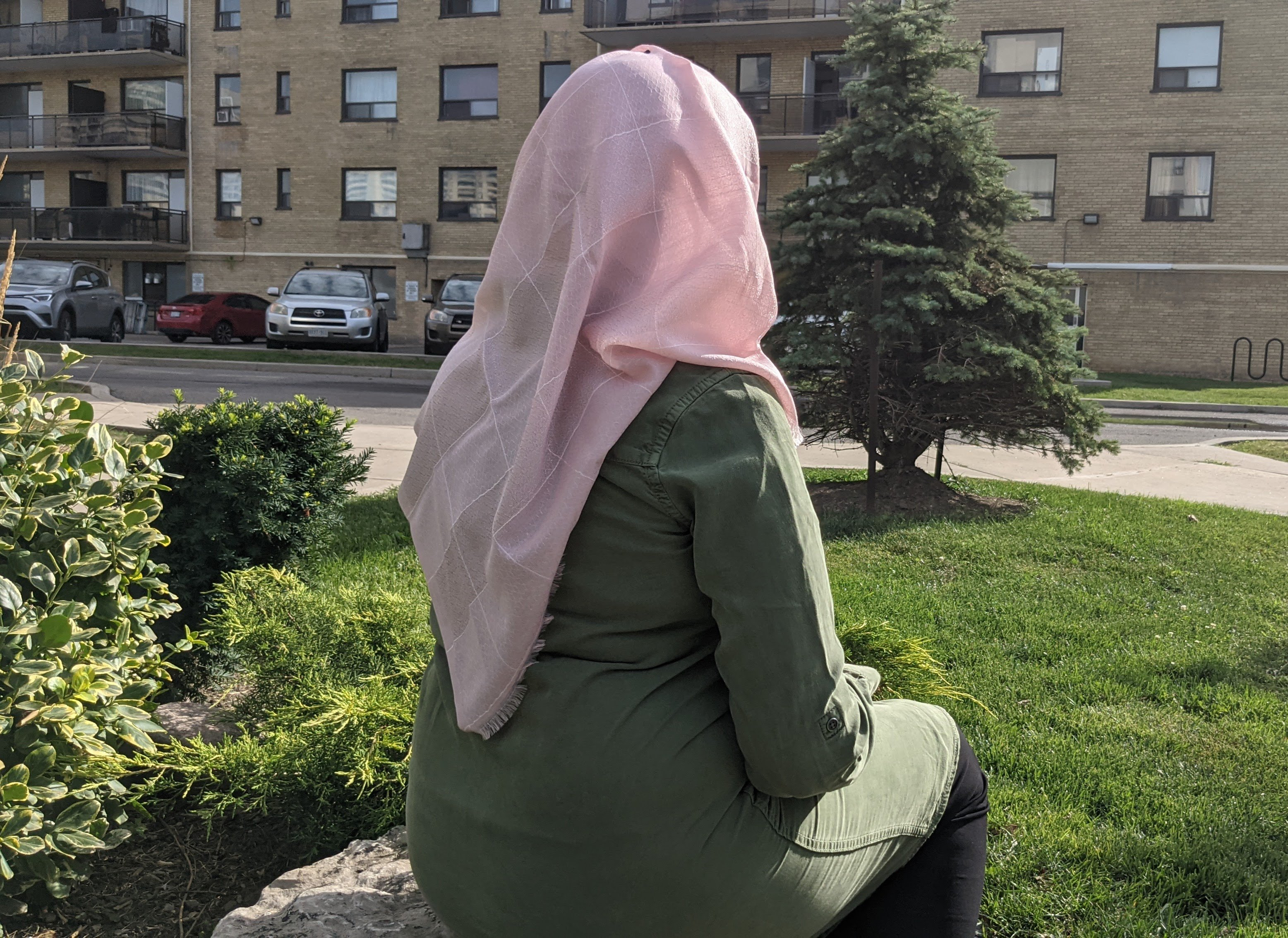 One of the Afghan refugees sitting outside in a garden with back turned to camera. Her identity is being withheld to protect her family.