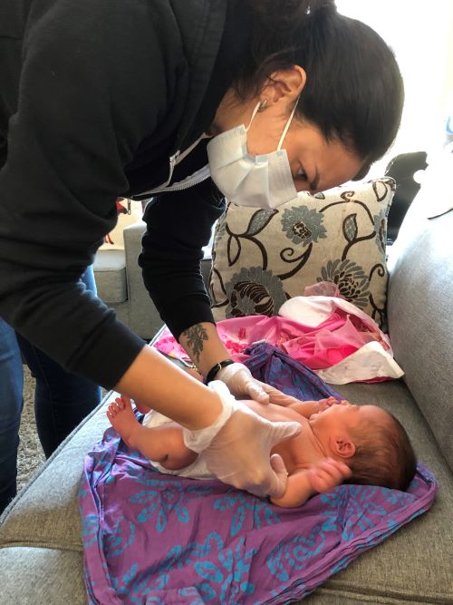 Indigenous Midwife Emily Chartrand Hudson examining baby at K'Tigaaning Indigenous Midwifery Program
