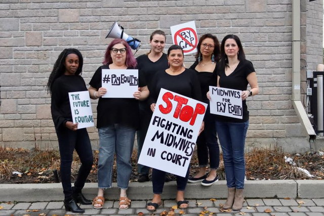 Midwives Althea Jones, Mandy Levencrown, Brittany-Lyne Carriere, Tammy Roberts, Jasmin Tecson and Kim Cloutier Holtz celebrate the win for midwives at the Ontario Court of Appeal and call on government to stop fighting midwives in court and close the gender wage gap. (CNW Group/Association of Ontario Midwives)