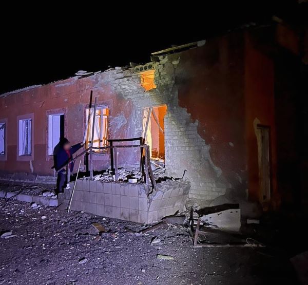 Bombed and crumbling hospital facade at night