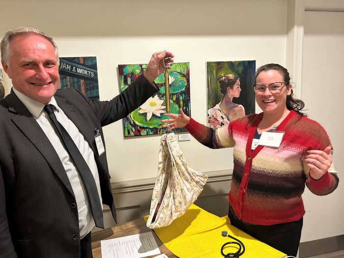 John Vanthorp MPP weighs baby doll in a sling scale with Indigenous Midwife Ashley Lickers.