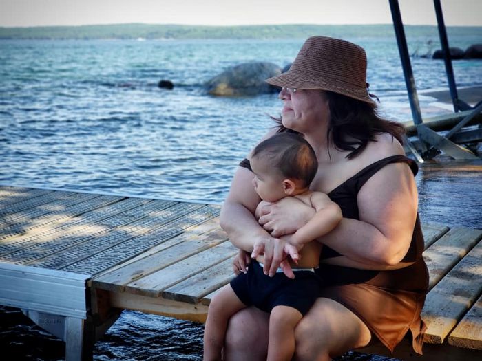 Woman and young child sitting on a dock by the water. 