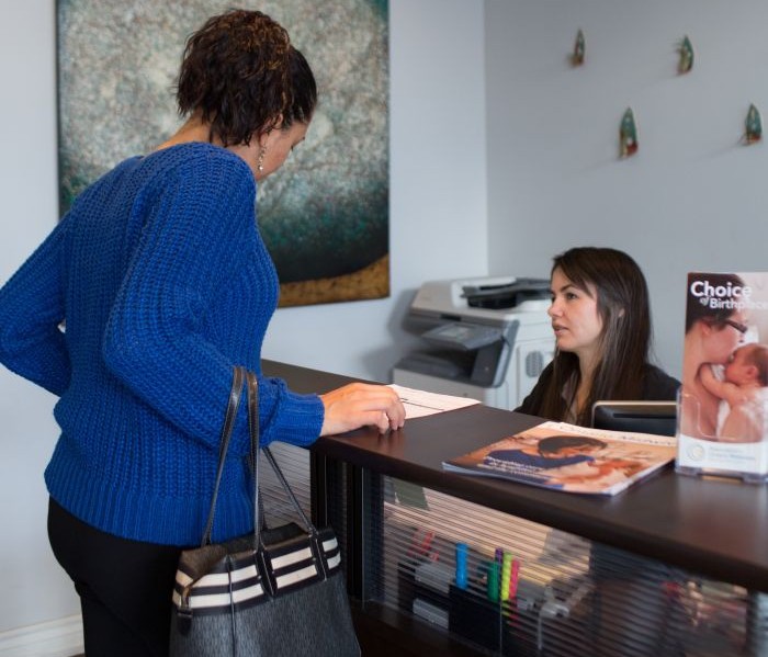Prospective client checking in at front desk of midwifery clinic.