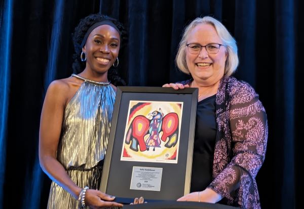 A-O-M President Althea Jones presents former C-E-O Kelly Stadelbauer with a plaque commemorating her 18-year tenure at the A-O-M.