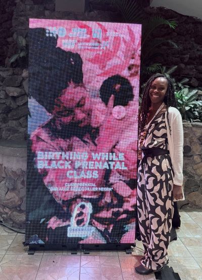 Althea standing beside digital poster.
