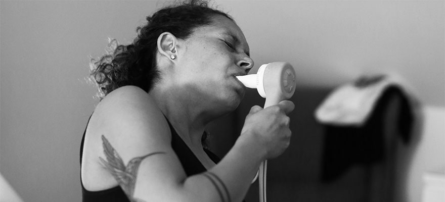Woman breathing in gas from a device in her mouth.