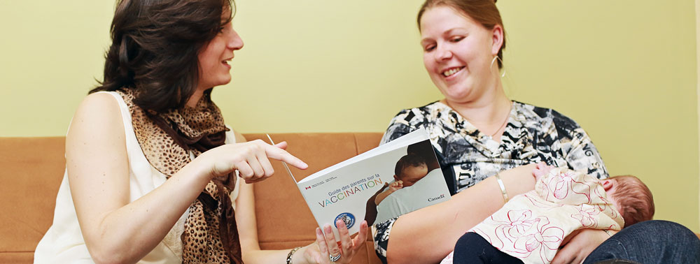 Midwife and client with baby discuss vaccination